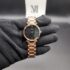 Dior style women's luxury watch featuring a faceted diamond-cut rose gold bezel, a shimmering black starry night sky dial, and a polished black link bracelet held in a black gloved hand.