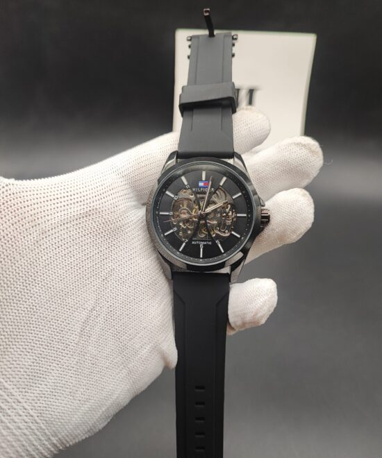Tommy Hilfiger style men's automatic skeleton watch featuring a polished black case, a matching black outer dial ring, an exposed mechanical core,
