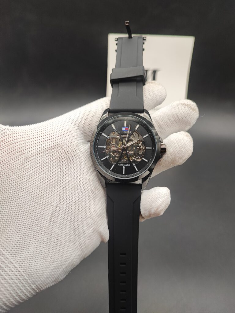 Tommy Hilfiger style men's automatic skeleton watch featuring a polished black case, a matching black outer dial ring, an exposed mechanical core,